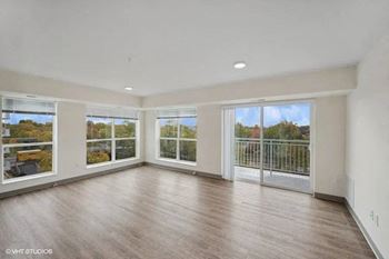 an empty living room with wood floors and large windows